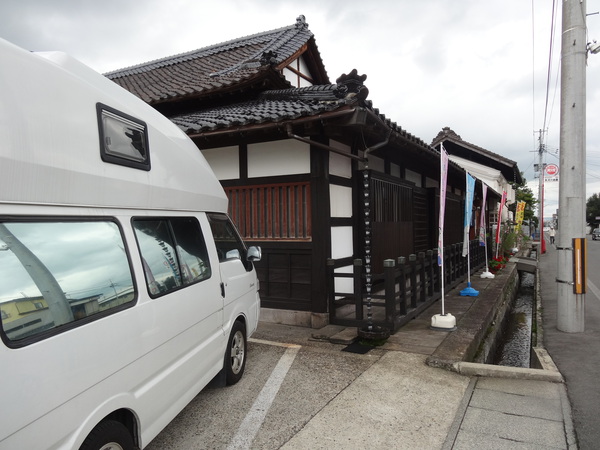 東光の酒蔵の蔵造りの建物と停めた軽キャンピングカー